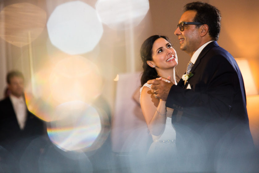 Bride smiles at her father during father daughter dance at her wedding