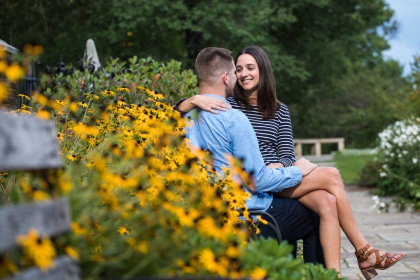 Engaged couple snuggling by black eyed susans