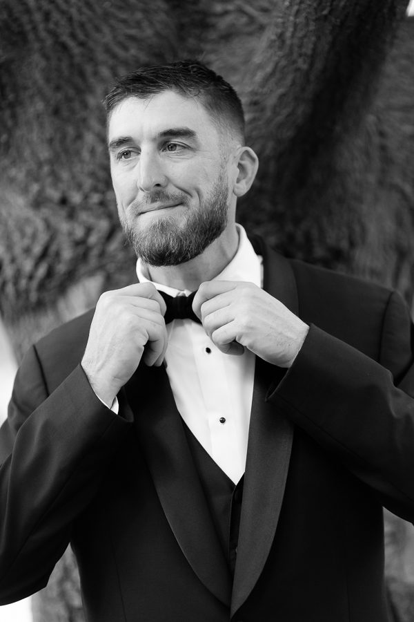 Classic groom portrait adjusting bowtie