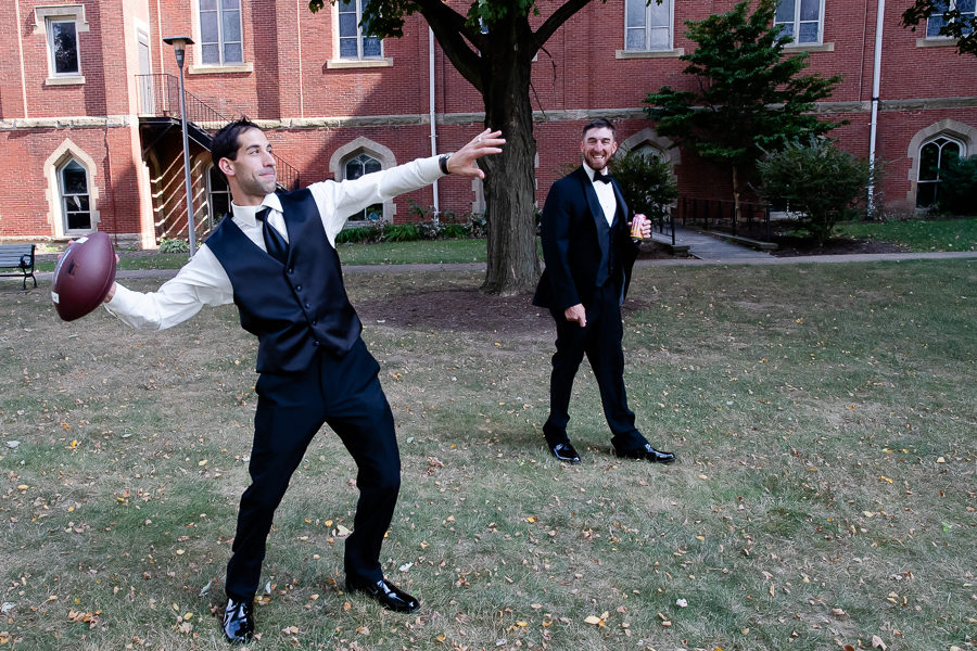 Groom and groomsman playing football before the wedding