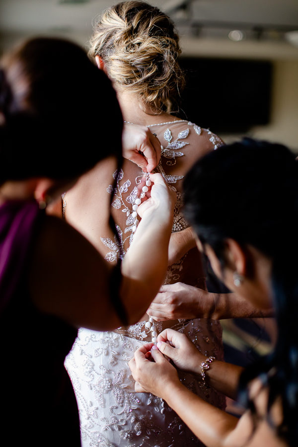 Bridesmaids buttoning Justin Alexander gown